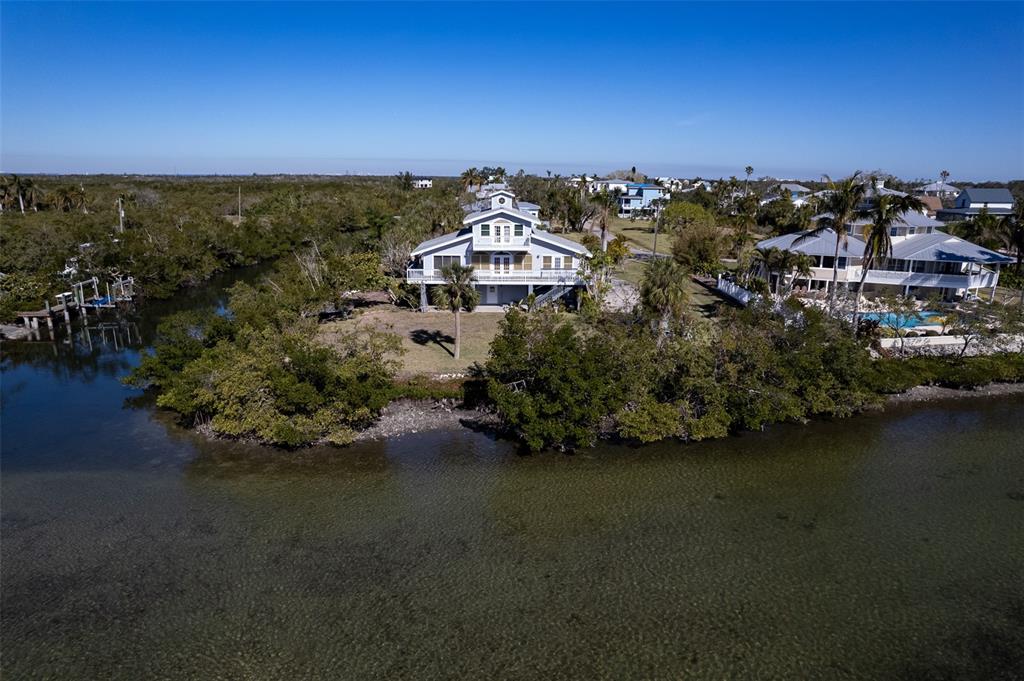 An aerial view shows a multi-story house situated on a waterfront lot with mangroves — 145 BURNS ROAD, TERRA CEIA, FL