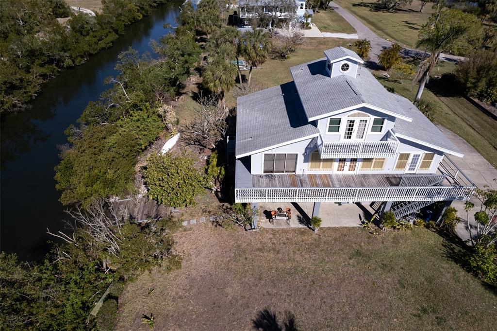 An aerial view of a multi-story house with a large deck overlooking a narrow canal — 145 BURNS ROAD, TERRA CEIA, FL