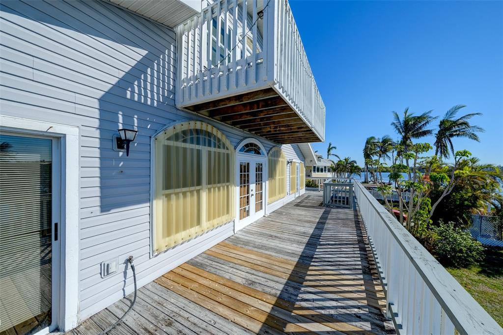 A wooden deck with a white railing overlooks a waterfront area with palm trees — 145 BURNS ROAD, TERRA CEIA, FL
