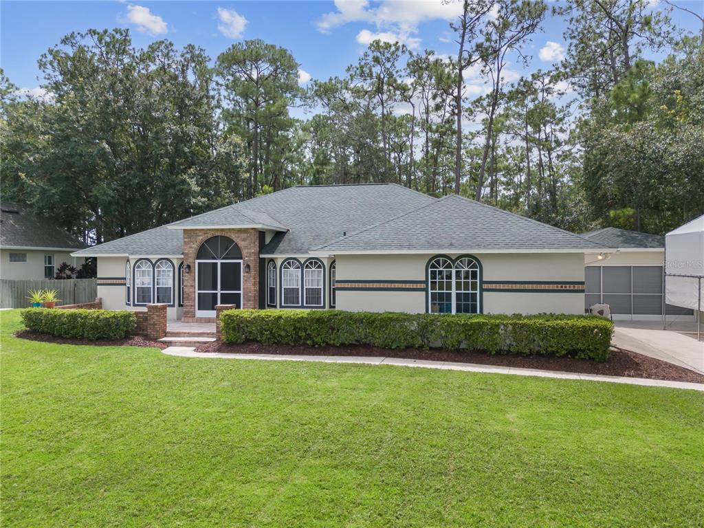 A single-story house with a brick entryway, arched windows, and a green shingled roof — 14612 BRAY ROAD, ORLANDO, FL