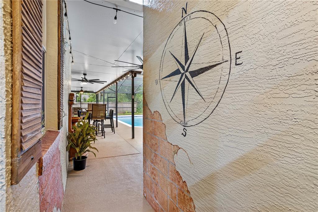 A covered patio features a painted compass mural on a wall and a swimming pool — 14612 BRAY ROAD, ORLANDO, FL
