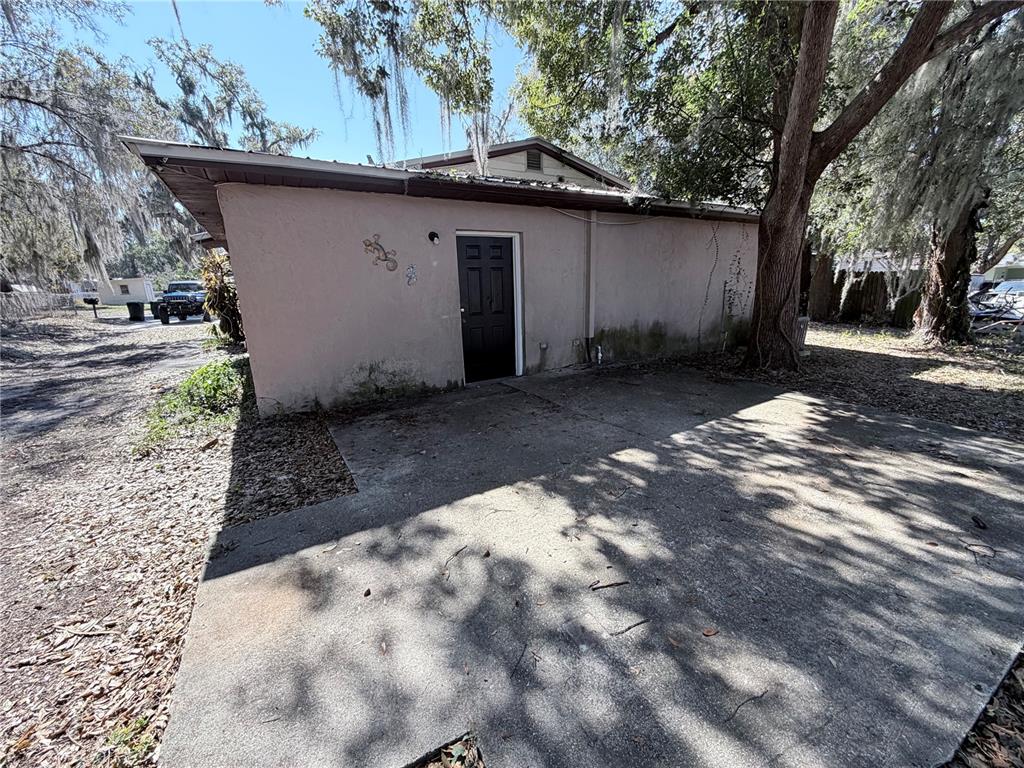 A concrete patio sits in front of a light-colored building with a black door — 670 GARDEN STREET, BARTOW, FL