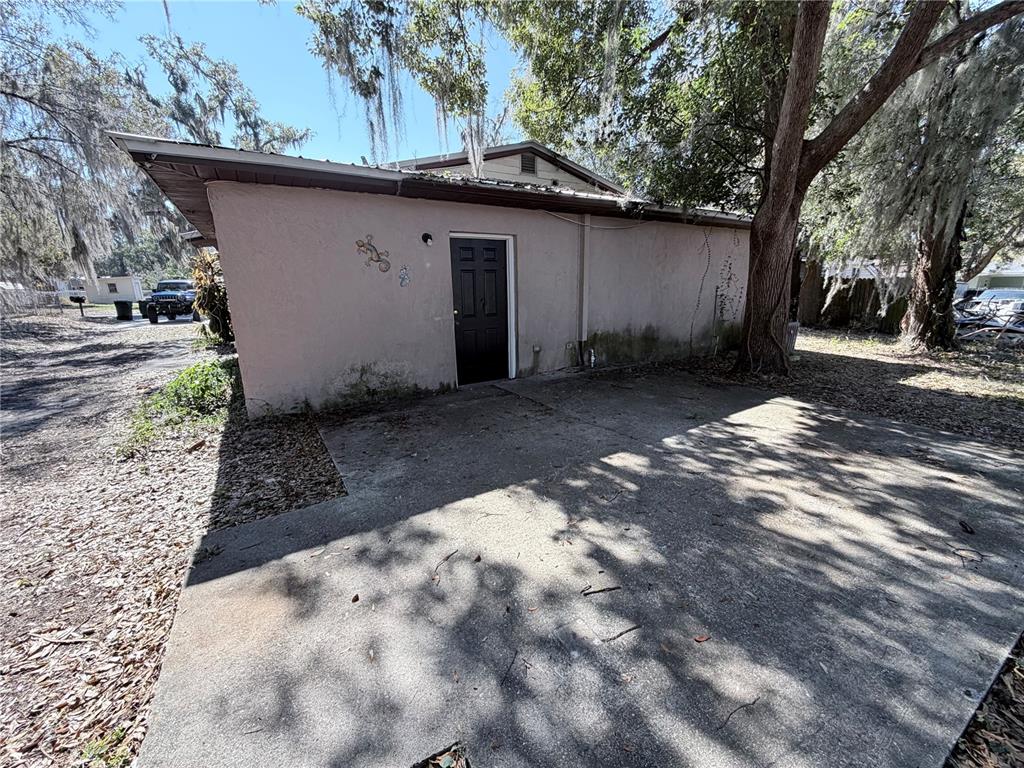 A concrete patio sits in front of a tan exterior wall with a black door — 670 GARDEN STREET, BARTOW, FL