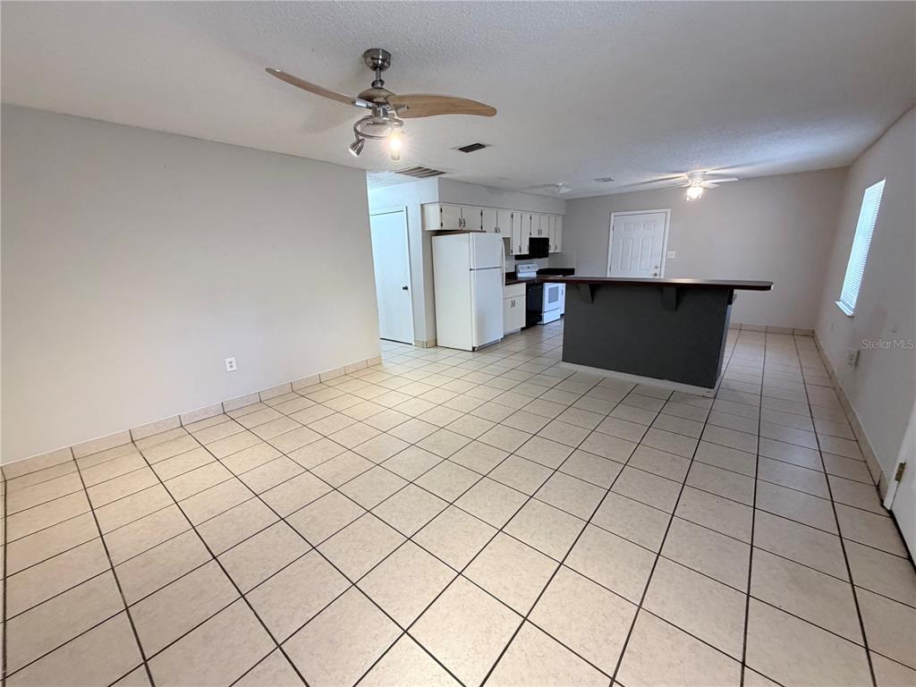 An open-concept kitchen and dining area features white cabinets, a dark breakfast bar, and tiled flooring — 670 GARDEN STREET, BARTOW, FL