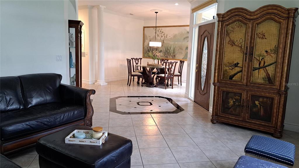 A living room with tile floors leads to a dining area with a large armoire — 2377 BURTON LANE, SARASOTA, FL