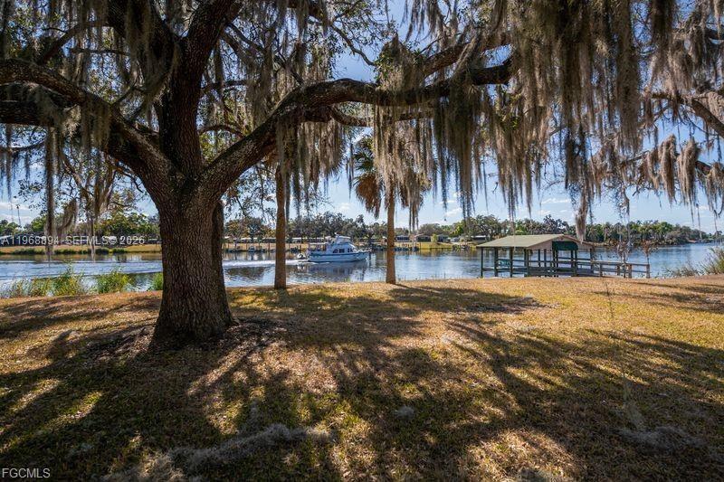 A large oak tree with Spanish moss overlooks a river with a boat and dock — 1209 County Rd 78, La Belle FL 33935, LA BELLE, FL