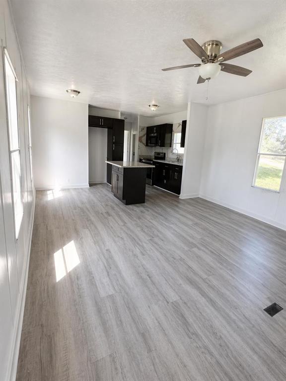 An open-concept kitchen with dark cabinets and a central island overlooks a light-floored living area — 4521 DUNKELD AVENUE, ORLANDO, FL