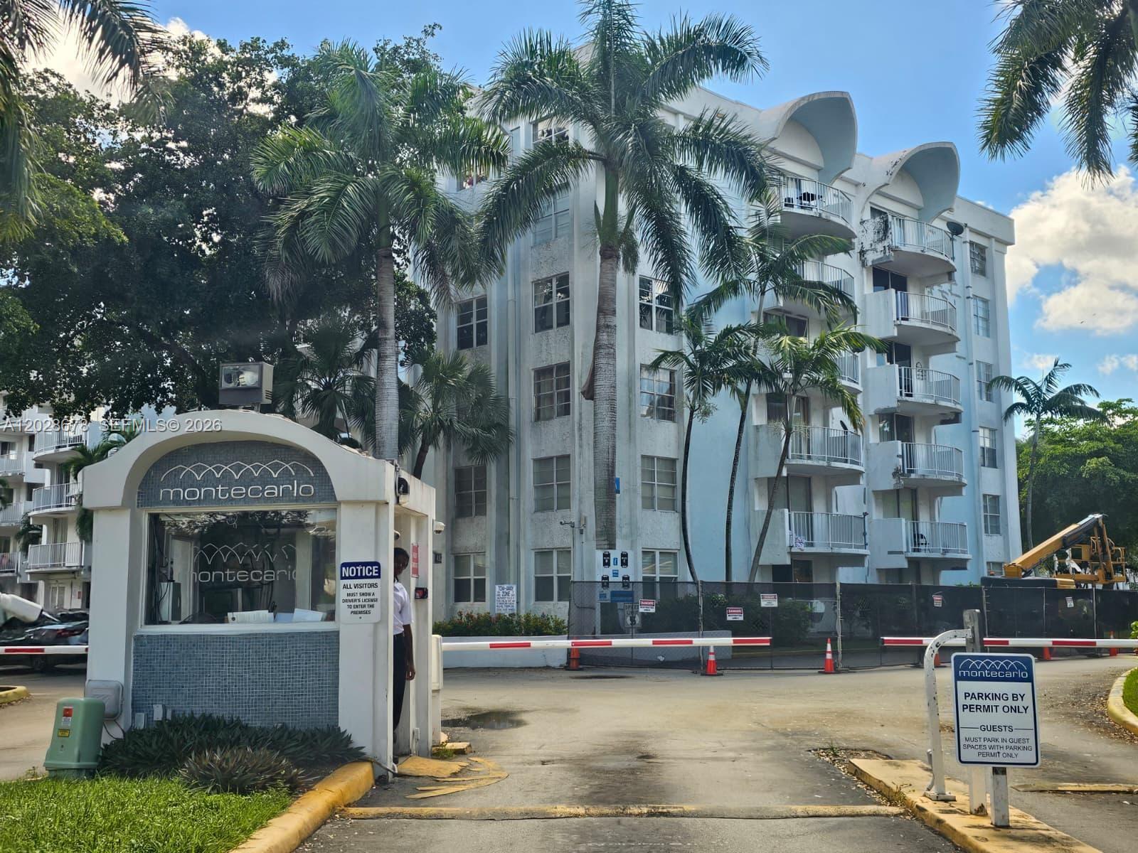 The exterior of the Montecarlo apartment complex features a gated entrance with a security booth — 492 NW 165th St Rd # 211, Miami FL 33169, MIAMI, FL