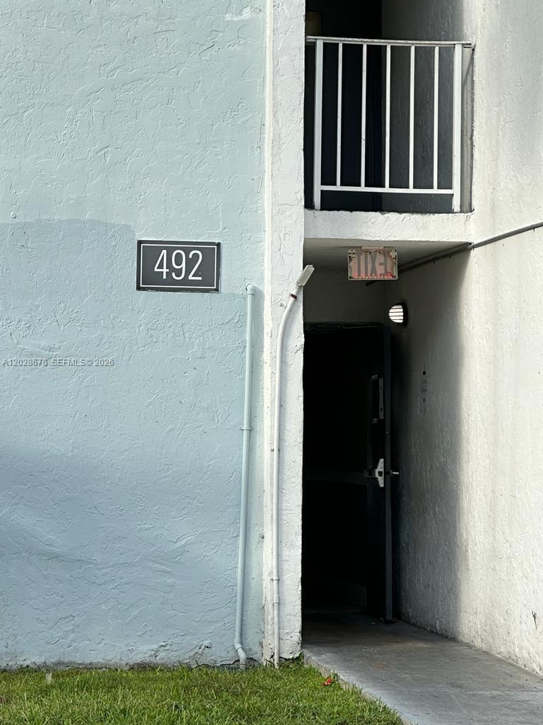 The exterior of a building shows a unit numbered 492 with an open doorway — 492 NW 165th St Rd # 211, Miami FL 33169, MIAMI, FL
