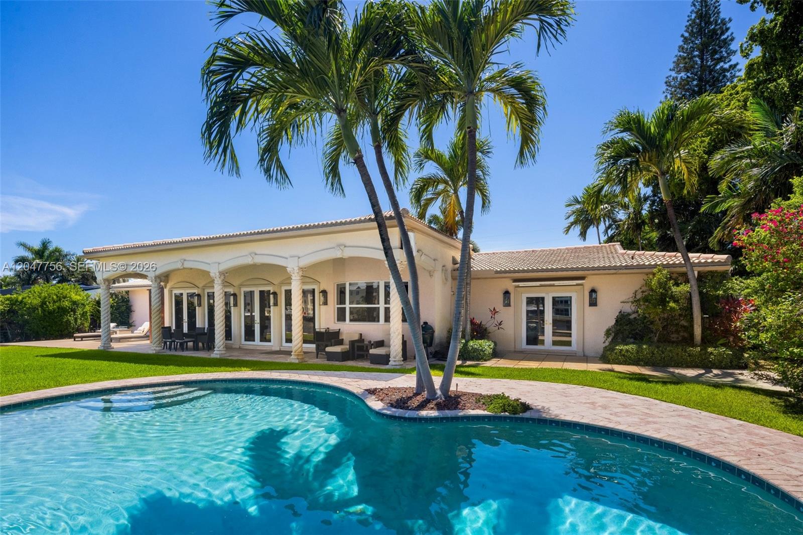 A backyard features a swimming pool, a covered patio with columns, and palm trees — 600 SE 28th Ave, Pompano Beach FL 33062, POMPANO BEACH, FL
