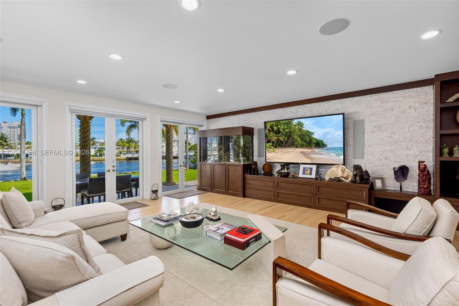 A living room features a large television, a fish tank, and glass doors overlooking water — 600 SE 28th Ave, Pompano Beach FL 33062, POMPANO BEACH, FL