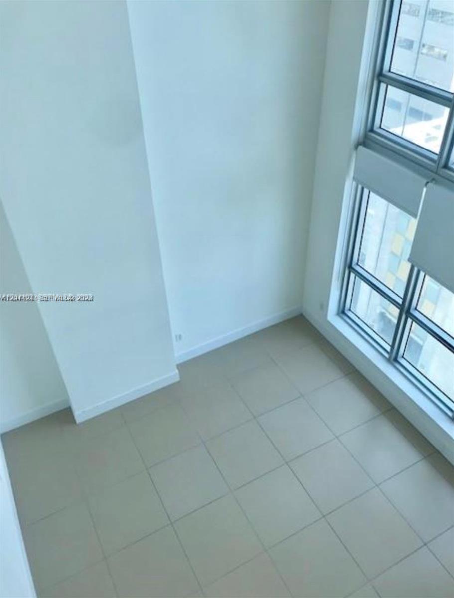 An empty room features light-colored tile flooring, white walls, and floor-to-ceiling windows — 300 S Biscayne Blvd # L32, Miami FL 33131, MIAMI, FL