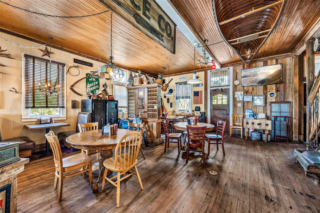 A rustic dining room features wood-paneled walls, a canoe hanging from the ceiling, and tables — 5390 HIGHWAY 1, GRANT VALKARIA, FL