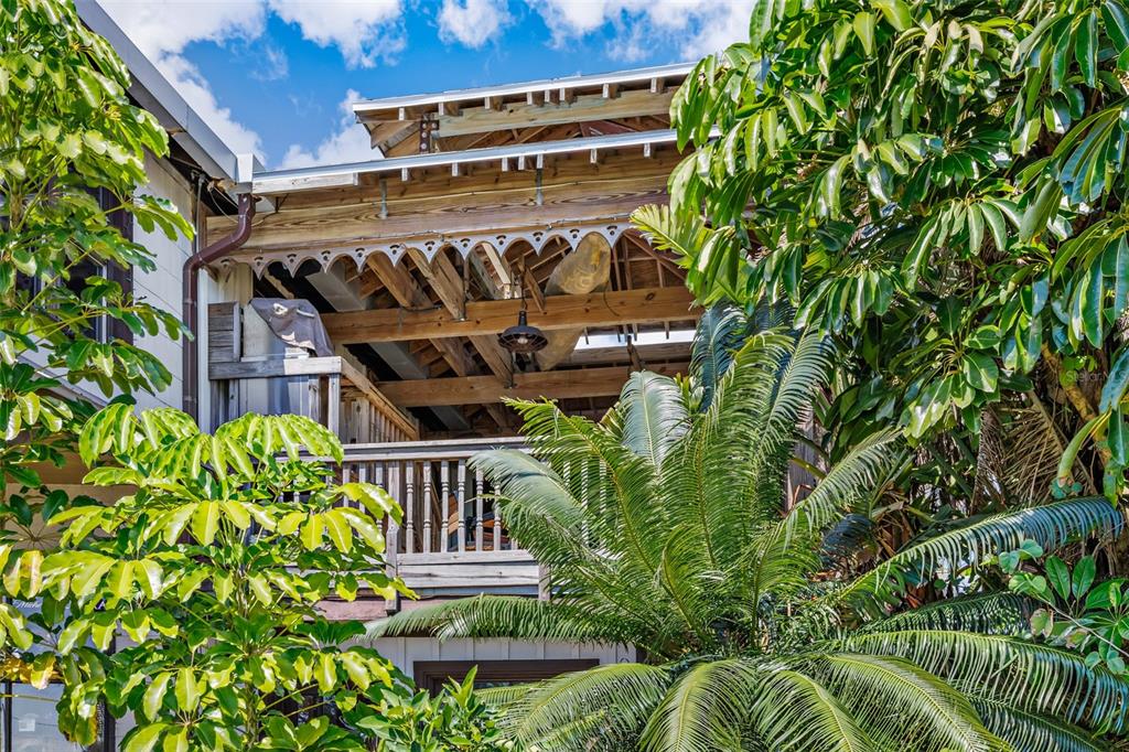 An exterior view of a wooden balcony with exposed rafters and decorative trim under foliage — 5390 HIGHWAY 1, GRANT VALKARIA, FL