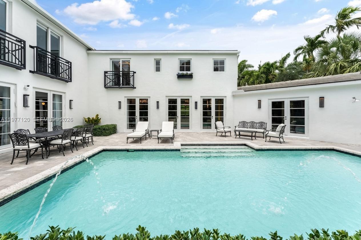 A white two-story house exterior features a swimming pool with fountains and a patio area — 2887 Pine Tree Dr, Miami Beach FL 33140, MIAMI BEACH, FL
