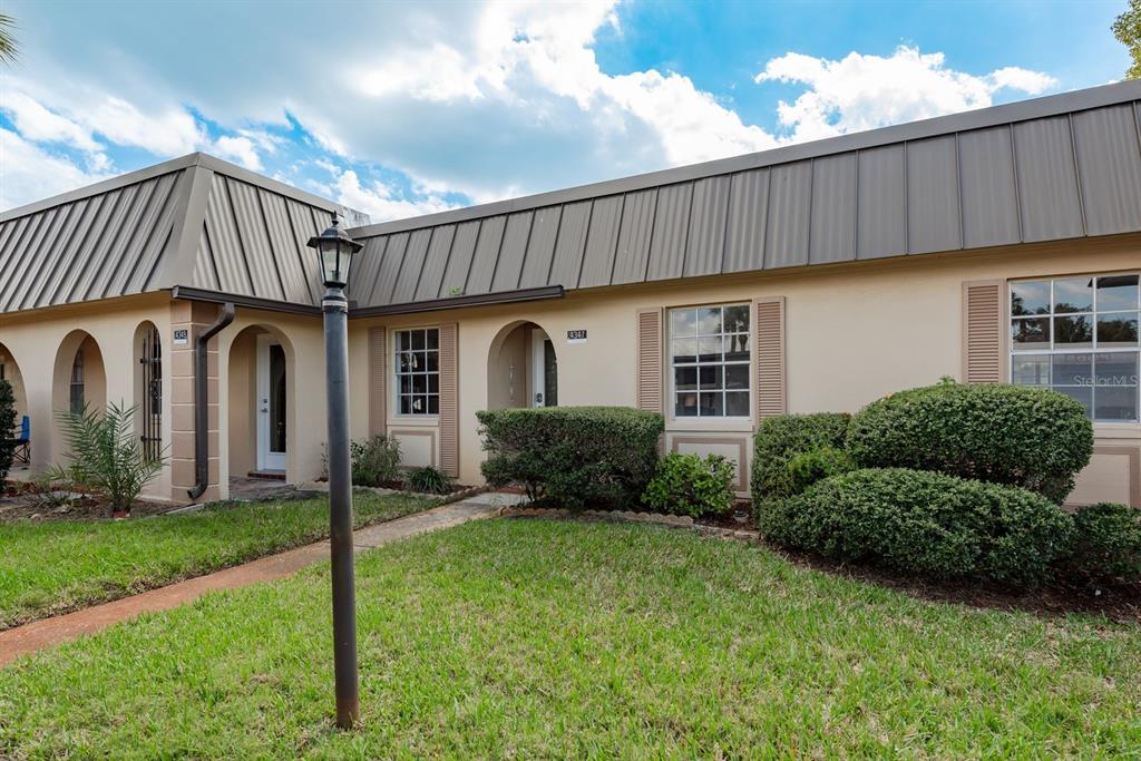 A single-story building with a metal mansard roof, arched entryways, and a front lawn — 4347 RUSTIC DRIVE UNIT 4347, NEW PORT RICHEY, FL