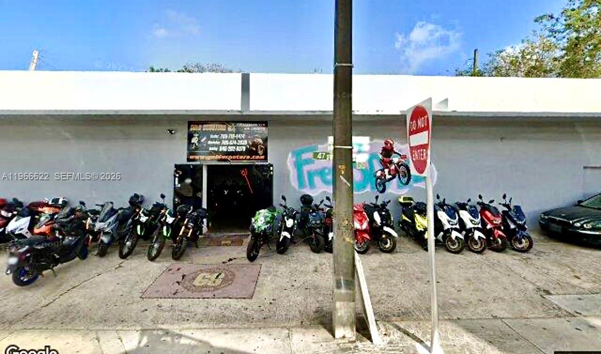 A storefront exterior features a row of parked motorcycles and scooters along a concrete wall — 4699 NW 27th Ave, Miami FL 33142, MIAMI, FL