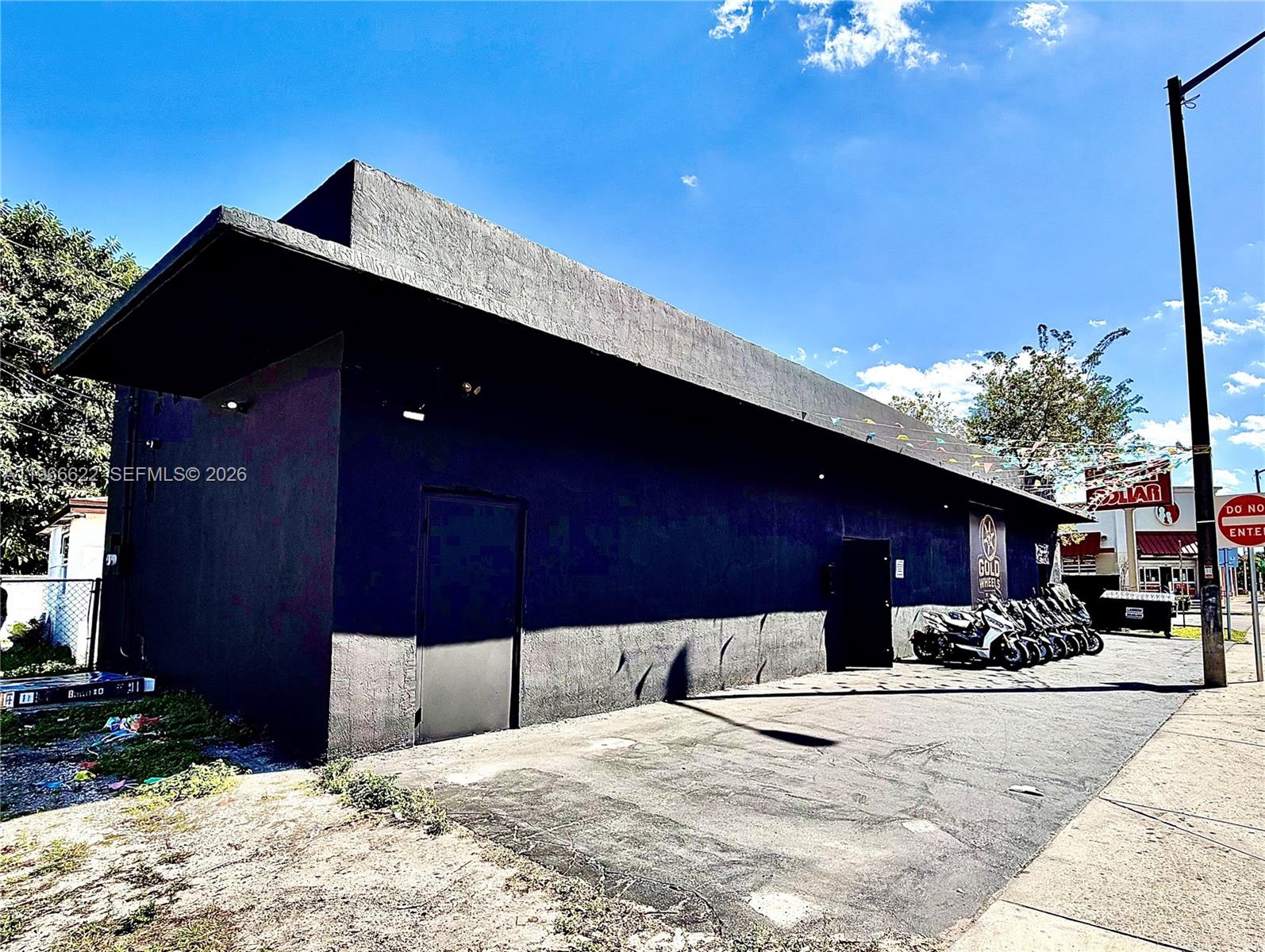 A black, flat-roofed commercial building with a paved parking area and several parked scooters — 4699 NW 27th Ave, Miami FL 33142, MIAMI, FL