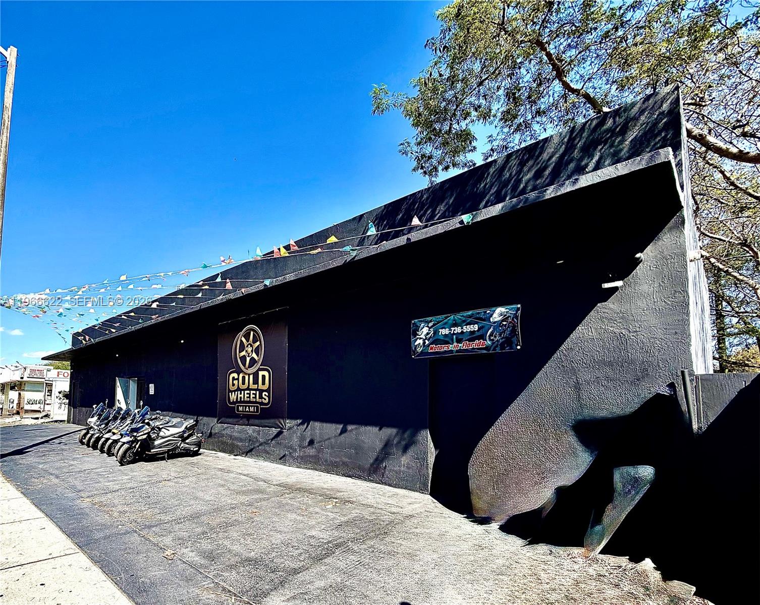 The exterior of a black commercial building features a Gold Wheels Miami sign and motorcycles — 4699 NW 27th Ave, Miami FL 33142, MIAMI, FL