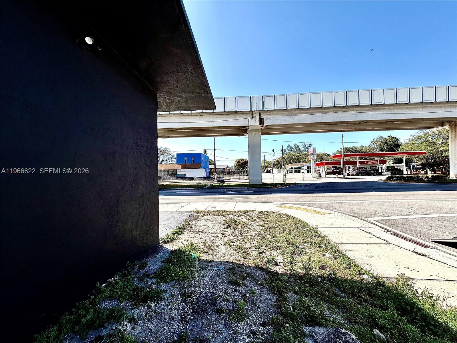 An exterior view shows a dark wall corner, a sidewalk, and an elevated highway overpass — 4699 NW 27th Ave, Miami FL 33142, MIAMI, FL