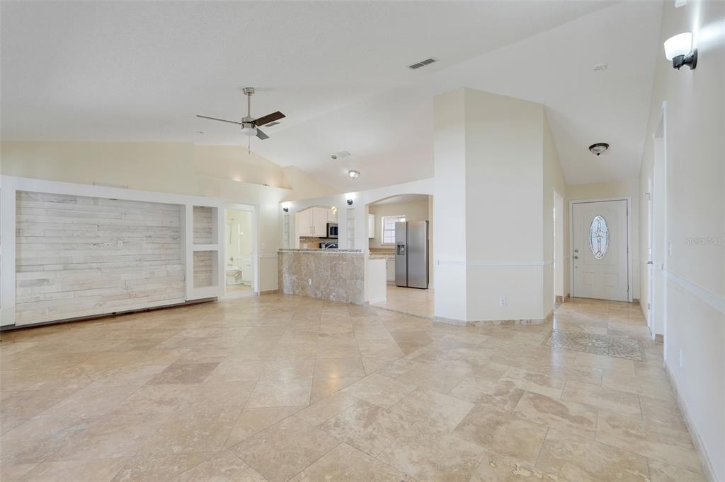 An open-concept living area features tile flooring, a stone-faced bar, and a white accent wall — 617 PARAKEET COURT, KISSIMMEE, FL