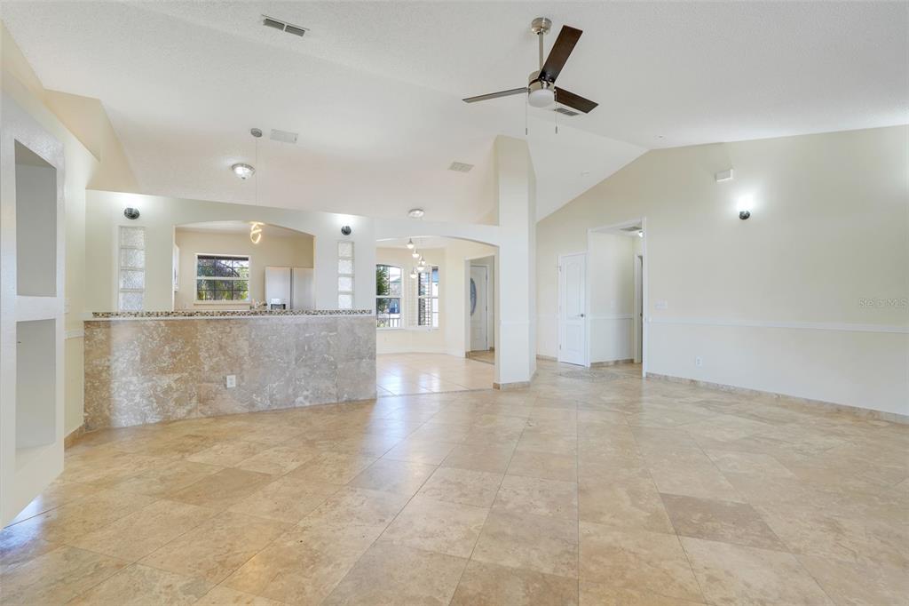 An open-concept living area features tile flooring, a stone-faced breakfast bar, and vaulted ceilings — 617 PARAKEET COURT, KISSIMMEE, FL