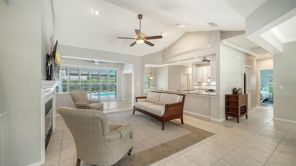 A living room with a fireplace, sofa, armchairs, and an open kitchen with tile floors — 4322 HIGHLAND OAKS CIRCLE, SARASOTA, FL