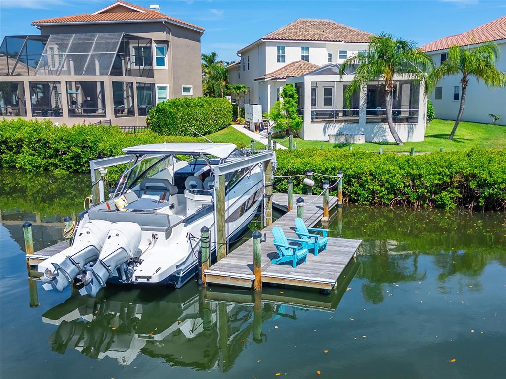 A boat on a lift and two chairs on a dock sit along a canal — 6203 MARBELLA BOULEVARD, APOLLO BEACH, FL