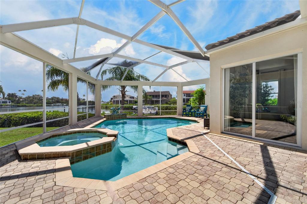 A screened-in patio features a swimming pool, a raised spa, and brick paver flooring — 6203 MARBELLA BOULEVARD, APOLLO BEACH, FL