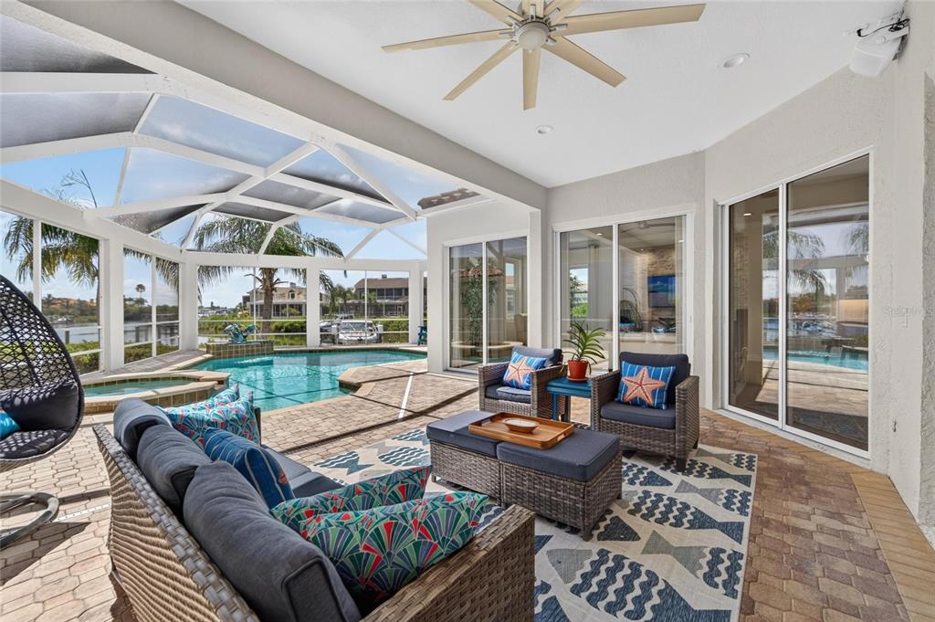 A covered patio features wicker furniture, a patterned rug, and a pool with a screen enclosure — 6203 MARBELLA BOULEVARD, APOLLO BEACH, FL