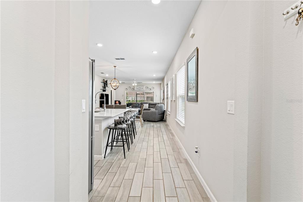 A hallway leads into an open-concept kitchen and living area with light wood-look tile flooring — 507 TYNES BOULEVARD, MIDDLEBURG, FL
