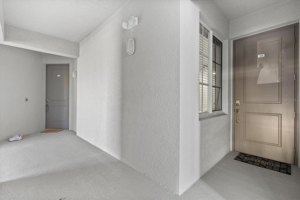 An exterior hallway shows two gray doors, a window, and a welcome mat — 17570 OPAL SAND DRIVE UNIT 302, VENICE, FL