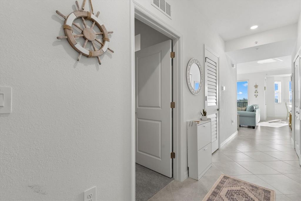 A hallway with tile flooring leads to a living area featuring a nautical wall decoration — 17570 OPAL SAND DRIVE UNIT 302, VENICE, FL