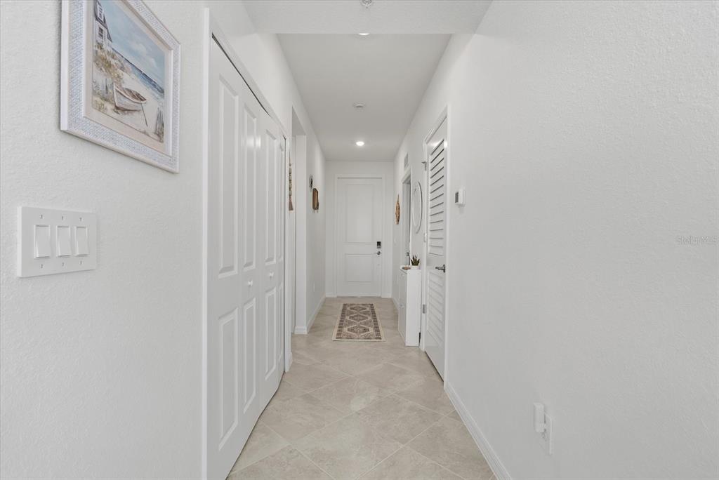 A bright hallway features white walls, tile flooring, and several closed doors — 17570 OPAL SAND DRIVE UNIT 302, VENICE, FL