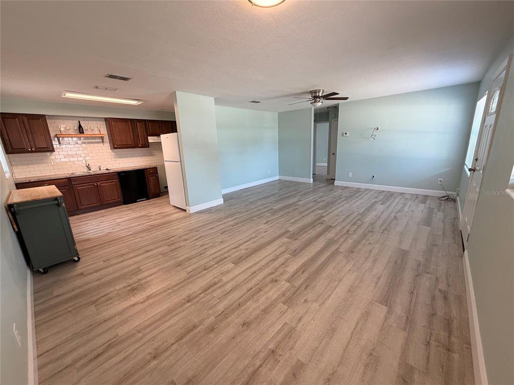 An open-concept kitchen and living area feature light wood-look flooring and white walls — 415 W EASY STREET, BARTOW, FL