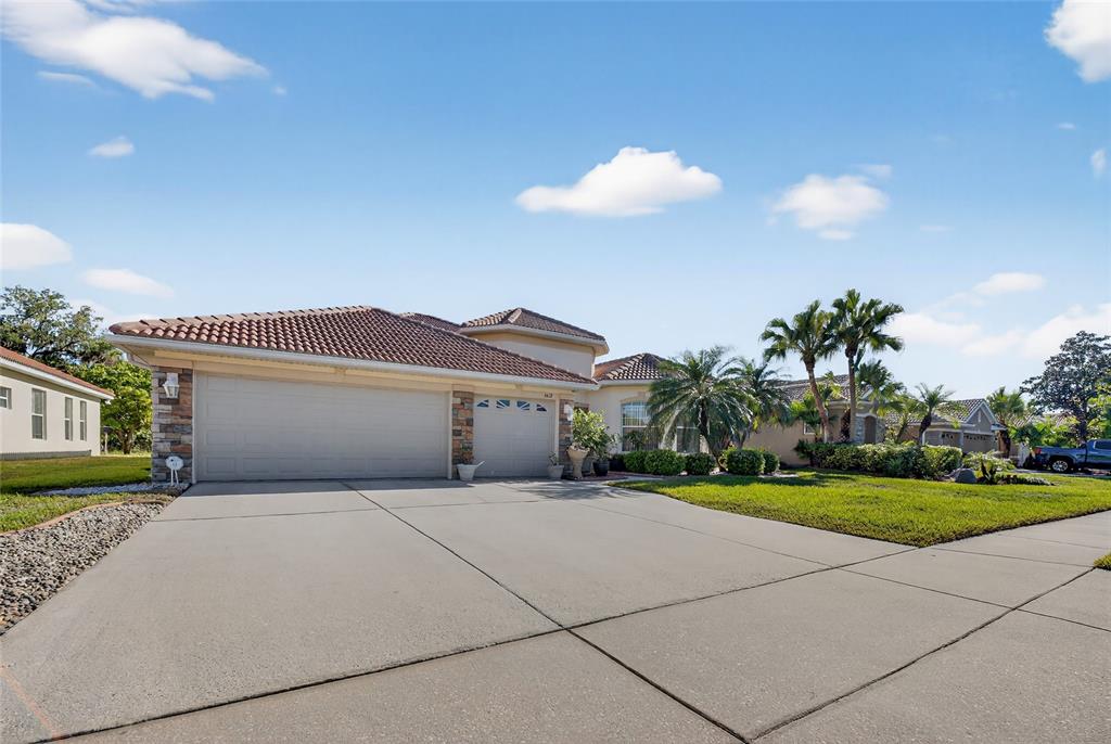 A single-story house with a tile roof, stone accents, and a three-car garage — 4612 E 62 AVENUE, BRADENTON, FL