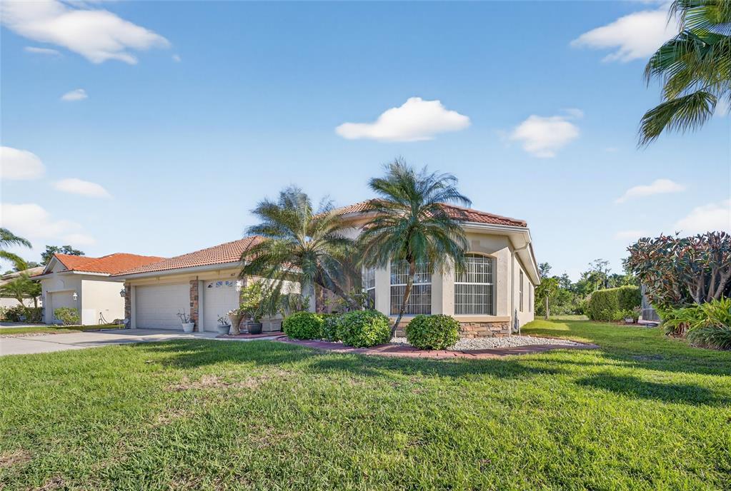 A single-story house with a tile roof, two-car garage, and palm trees in the front yard — 4612 E 62 AVENUE, BRADENTON, FL