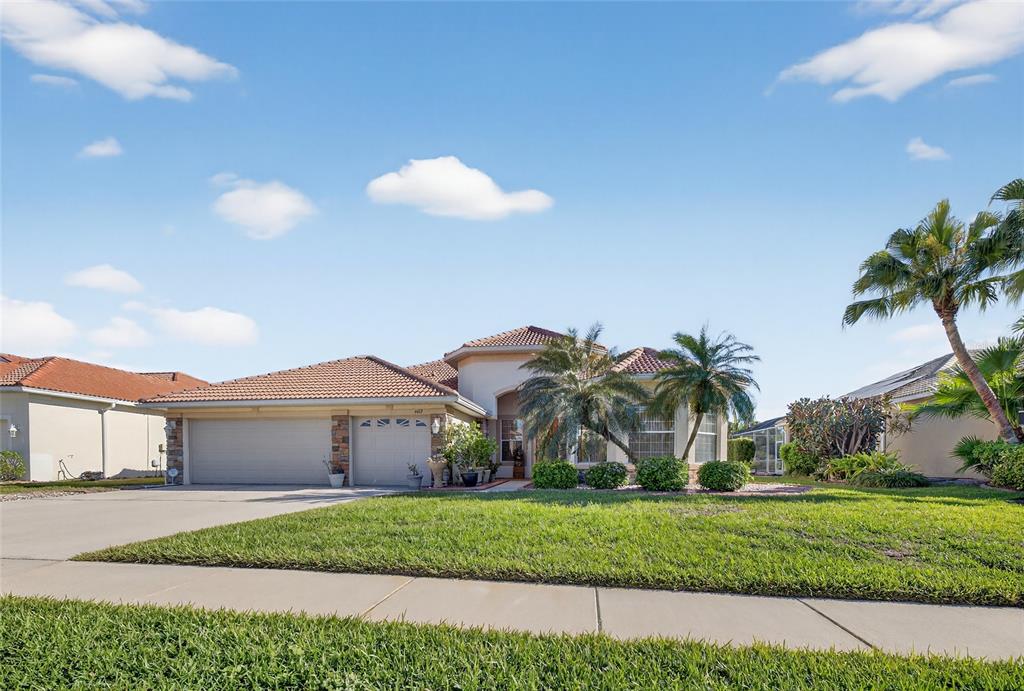 A single-story suburban house with a tile roof, three-car garage, and palm trees — 4612 E 62 AVENUE, BRADENTON, FL