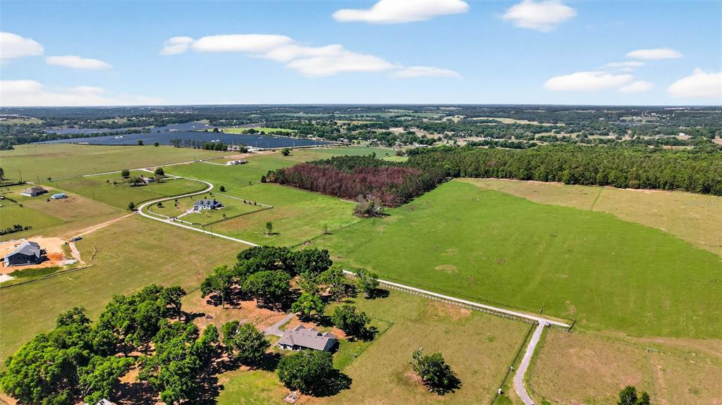 An aerial view shows a rural landscape with houses, pastures, and a large solar farm — 0 HILLTOP HORIZONS PLACE, DADE CITY, FL