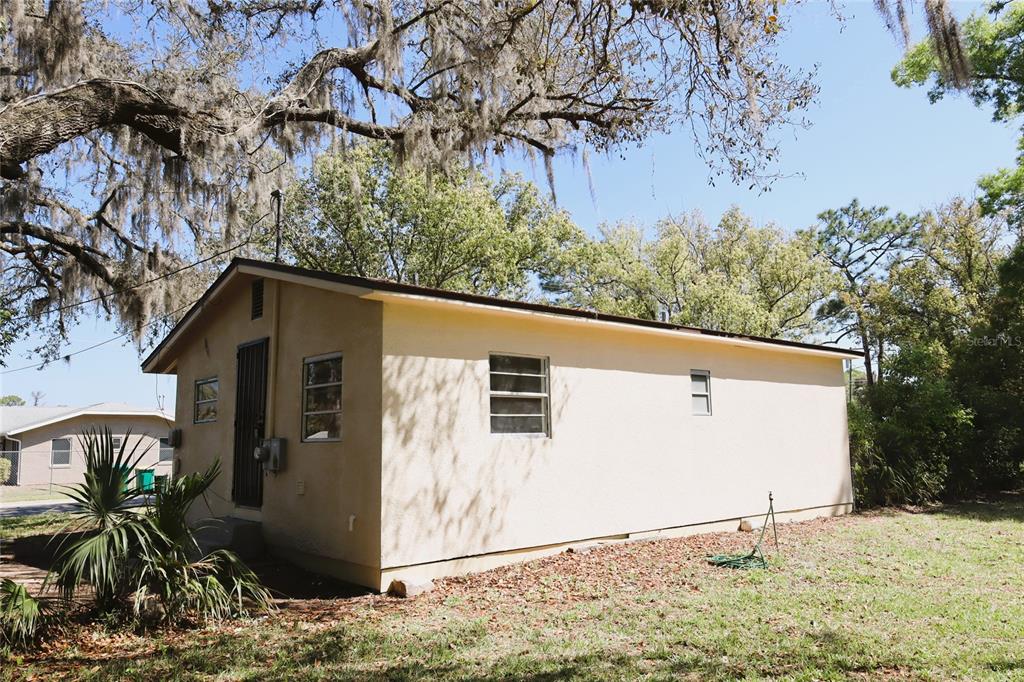 A large, grassy backyard features mature trees and a small fire pit area — 2024 DIXIE AVENUE, EUSTIS, FL