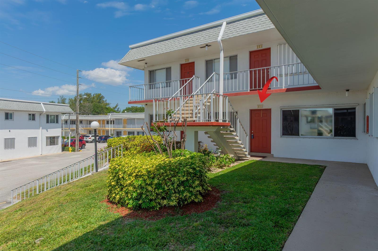 A red door marked 115 is visible on the ground floor of a two-story apartment building — 3120 Cynthia Lane # 115, FL 33461, FL