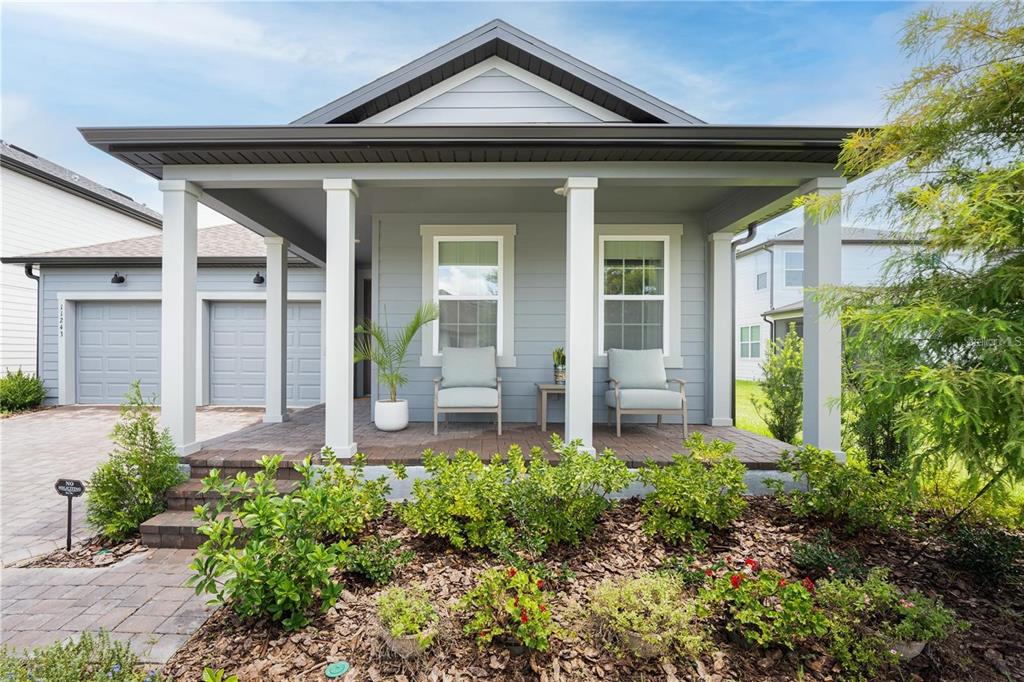 A gray house with a covered front porch, two chairs, and a paved driveway — 11243 PIXIE MANDARIN COURT, WINTER GARDEN, FL