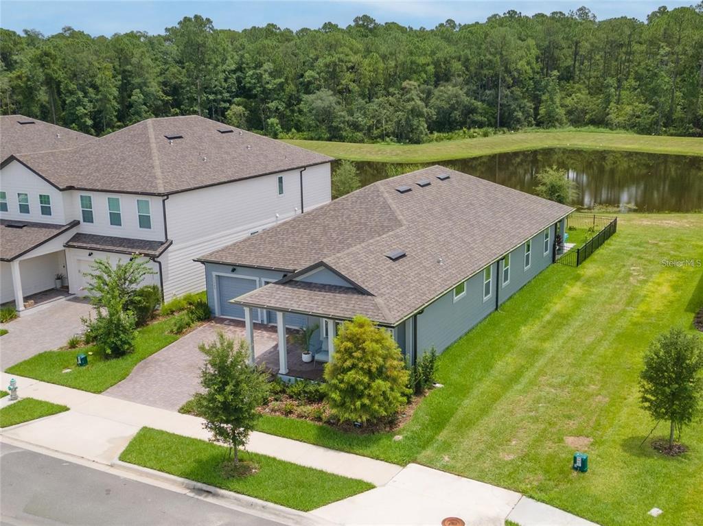 An aerial view shows a single-story house with a gray exterior, shingled roof, and backyard pond — 11243 PIXIE MANDARIN COURT, WINTER GARDEN, FL