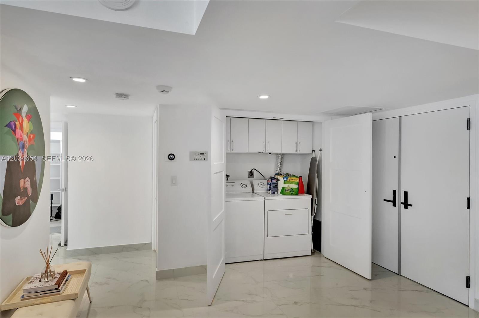 A laundry closet with white appliances and cabinets is situated in a room with tile flooring — 2 Grove Isle Dr # B706, Miami FL 33133, MIAMI, FL