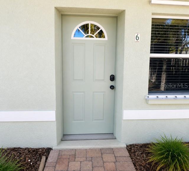 A light green front door with a semi-circular window sits beside a window with blinds — 9030 BLIND PASS ROAD UNIT D6, ST PETERSBURG, FL
