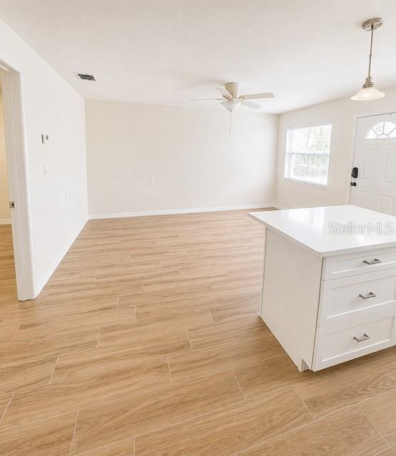 A bright room features light wood-look tile flooring, a ceiling fan, and a white kitchen island — 9030 BLIND PASS ROAD UNIT D6, ST PETERSBURG, FL