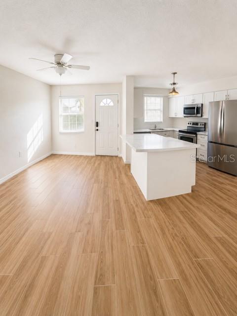 An open-concept kitchen and living area features light wood-look flooring and a white kitchen island — 9030 BLIND PASS ROAD UNIT D6, ST PETERSBURG, FL