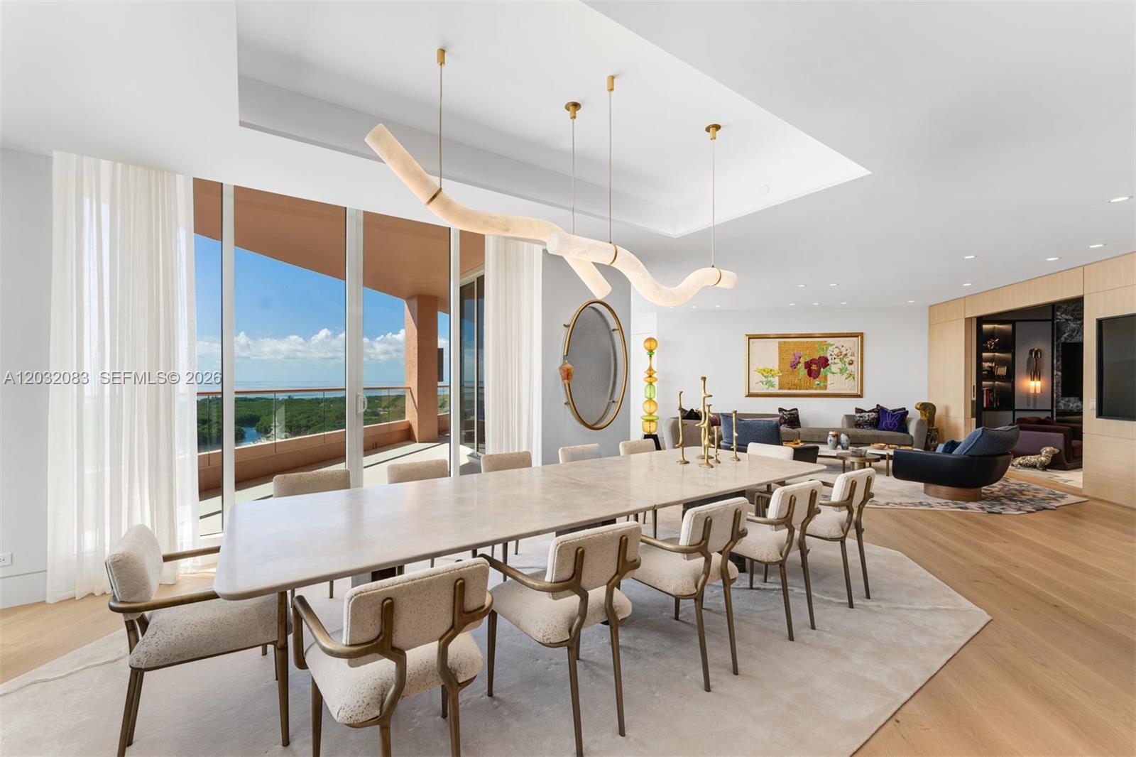 A dining room with a long stone table, sculptural light fixture, and floor-to-ceiling windows — 60 Edgewater Dr # D, Coral Gables FL 33133, CORAL GABLES, FL