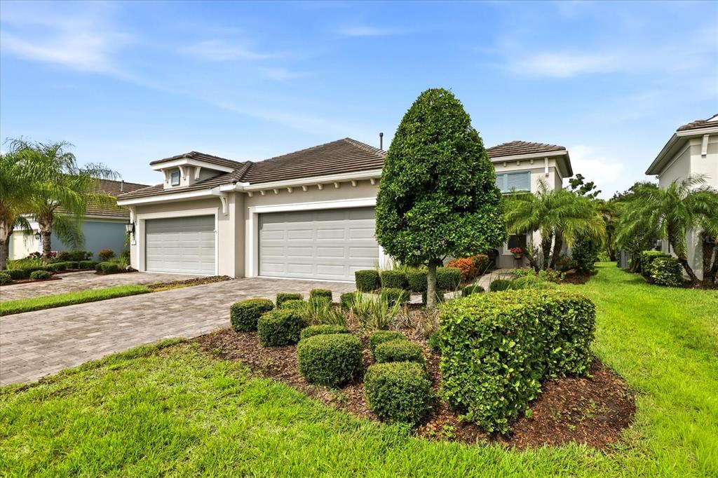 A suburban house exterior features a two-car garage, a paved driveway, and manicured landscaping — 3036 SKY BLUE COVE, LAKEWOOD RANCH, FL