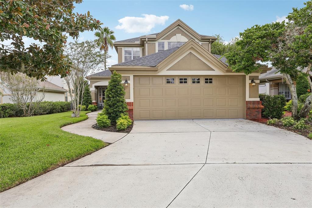 A two-story house features a tan exterior, a two-car garage, and a concrete driveway — 3050 SHOAL CREEK VILLAGE DRIVE, LAKELAND, FL